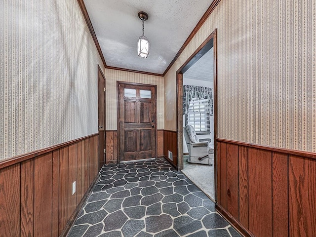 interior space featuring crown molding, dark carpet, a textured ceiling, and wood walls