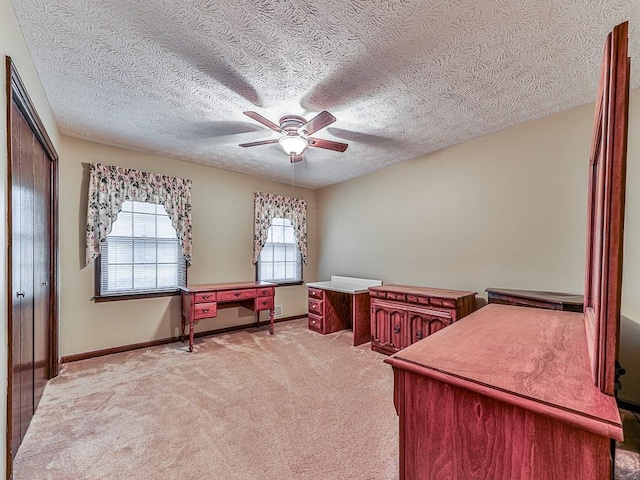 office featuring light carpet, a textured ceiling, and ceiling fan