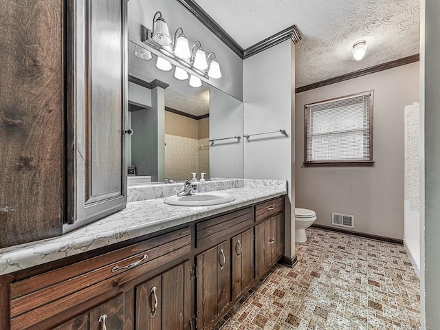 bathroom with vanity, a textured ceiling, ornamental molding, and toilet