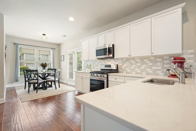 4003 Coachman Ct, Cumming, GA 30040 - kitchen with stainless steel appliances, tasteful backsplash, dark wood-type flooring, white cabinetry, and recessed lighting