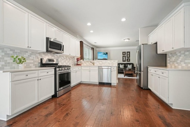 4003 Coachman Ct, Cumming, GA 30040 - kitchen with appliances with stainless steel finishes, a peninsula, white cabinets, decorative backsplash, and crown molding