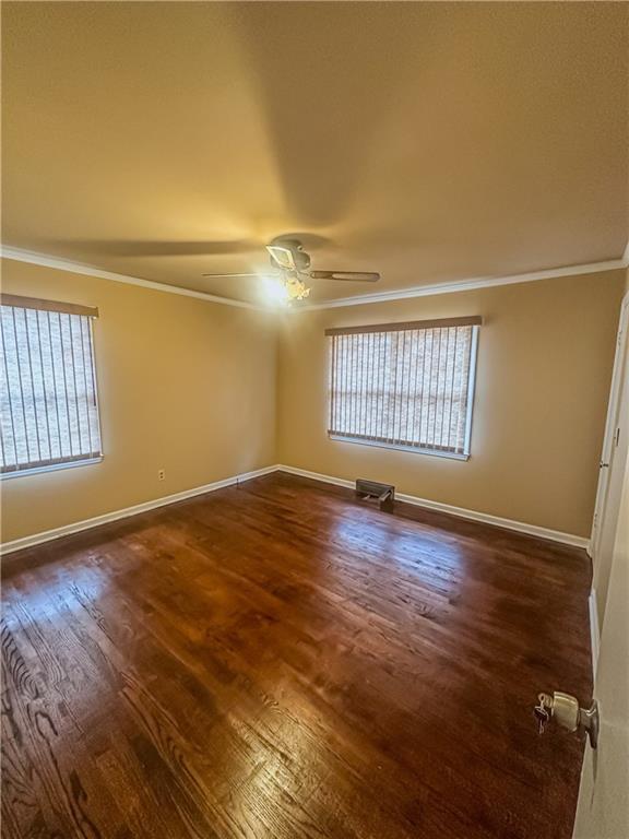 spare room with ornamental molding, dark wood-type flooring, and ceiling fan