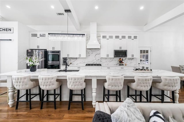 kitchen with visible vents, decorative backsplash, custom exhaust hood, a large island, and stainless steel appliances