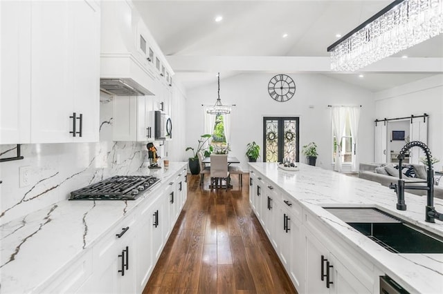 kitchen with dark wood-style flooring, vaulted ceiling, a sink, light stone counters, and glass insert cabinets