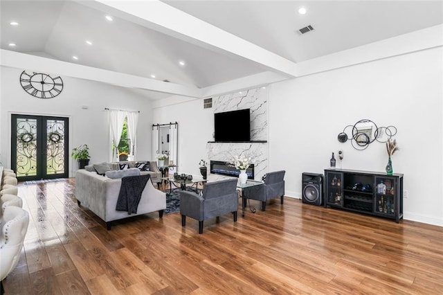 living area with french doors, visible vents, wood finished floors, and lofted ceiling