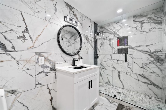 bathroom with tile walls, a tile shower, marble finish floor, and vanity