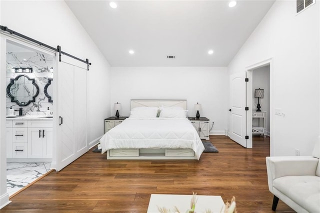 bedroom featuring a barn door, recessed lighting, wood finished floors, vaulted ceiling, and visible vents