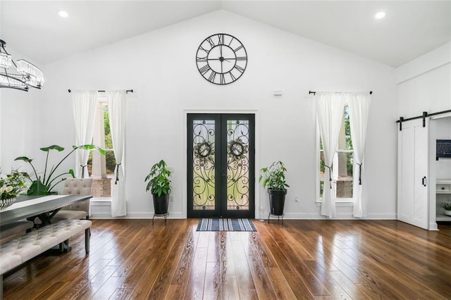 entrance foyer featuring hardwood / wood-style floors, high vaulted ceiling, french doors, and a barn door