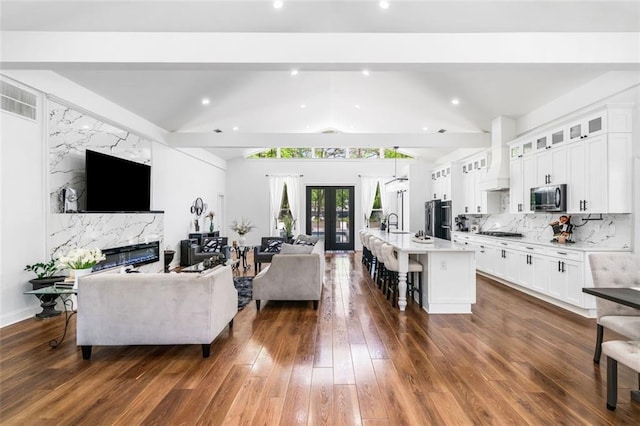 living area with vaulted ceiling with beams, french doors, dark wood-style floors, and a premium fireplace