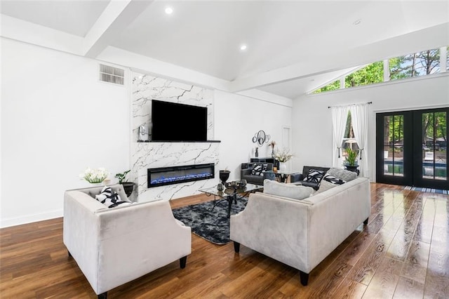 living area featuring a fireplace, vaulted ceiling, wood finished floors, and visible vents