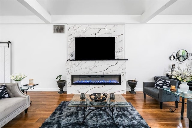 living room featuring baseboards, a barn door, wood finished floors, and a fireplace