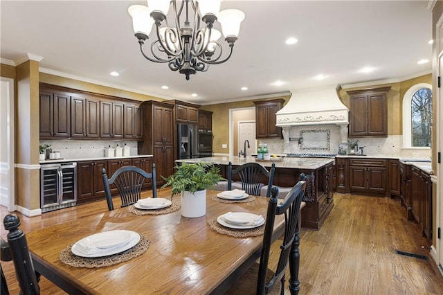 dining room with ornamental molding, beverage cooler, and light wood-type flooring