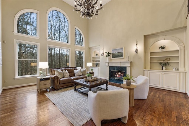 living room with built in shelves, a high end fireplace, and dark hardwood / wood-style floors