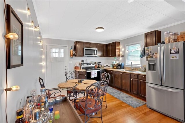 living area with ornamental molding, wood finished floors, a ceiling fan, and baseboards