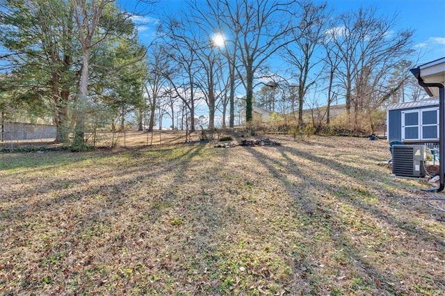 view of yard featuring fence, an outdoor structure, and central air condition unit