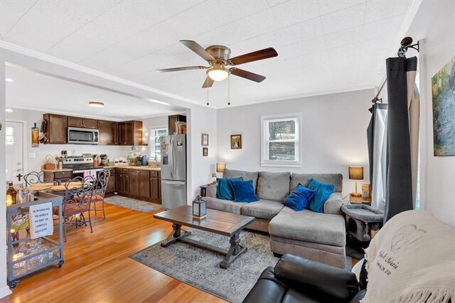 living room with light wood-style flooring, ornamental molding, and ceiling fan