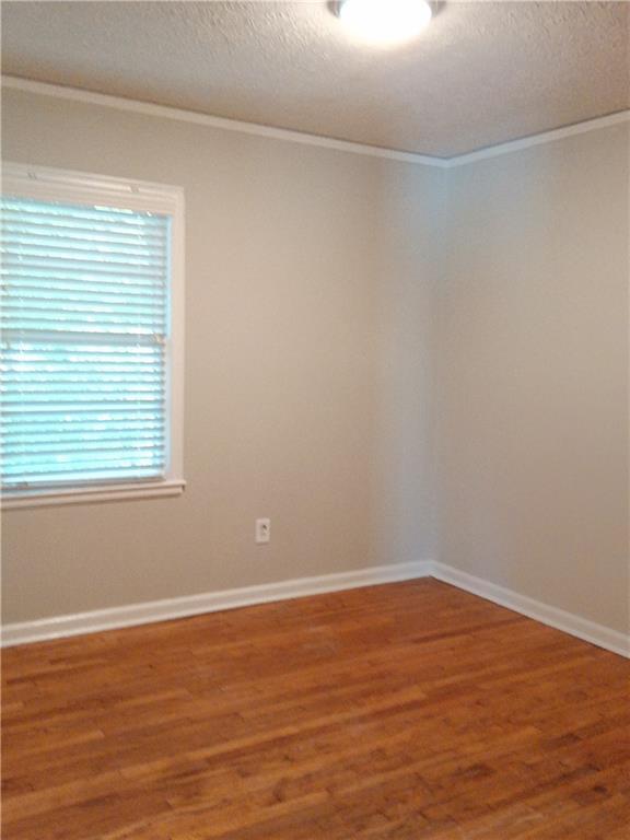 732 Vinson Pl SW, Atlanta, GA 30315 - spare room featuring ornamental molding, a textured ceiling, wood finished floors, and baseboards