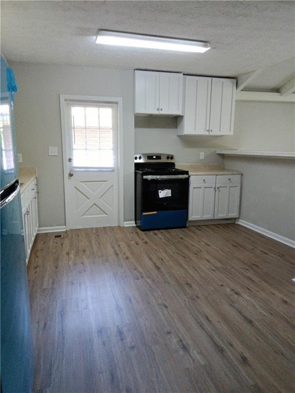 732 Vinson Pl SW, Atlanta, GA 30315 - kitchen with stainless steel appliances, wood finished floors, white cabinets, baseboards, and a textured ceiling