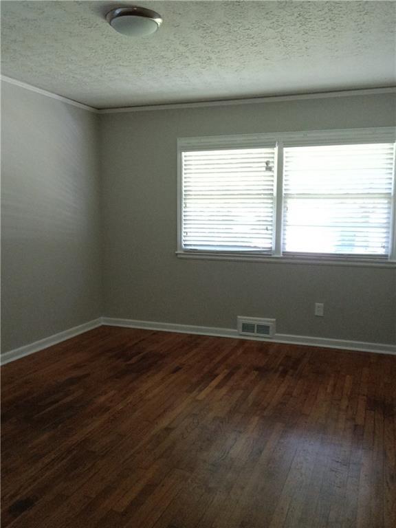 732 Vinson Pl SW, Atlanta, GA 30315 - unfurnished room featuring dark wood-type flooring, healthy amount of natural light, crown molding, a textured ceiling, and baseboards
