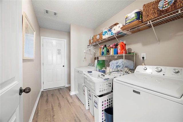 102 Autumn Brooke Trl, Dallas, GA 30157 - clothes washing area with washing machine and clothes dryer, light wood-style flooring, baseboards, and a textured ceiling