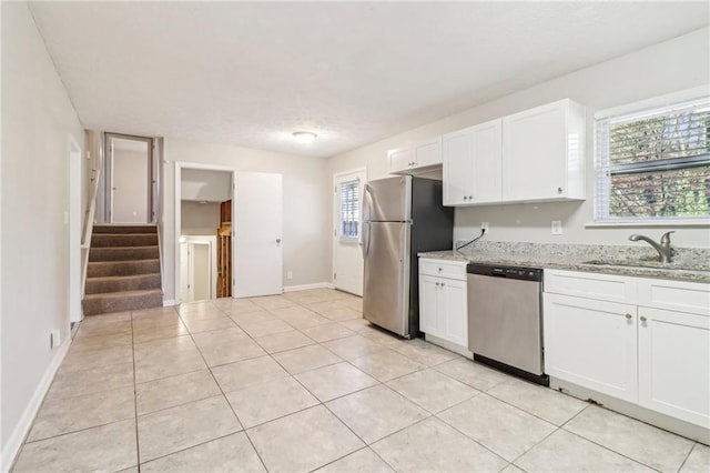 kitchen featuring sink, light stone counters, light tile patterned floors, stainless steel appliances, and white cabinets