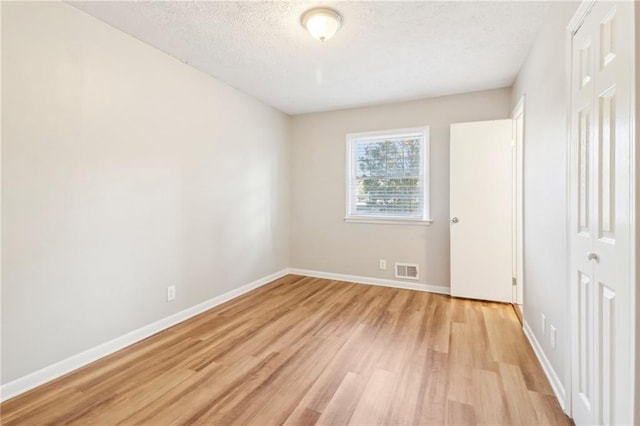 unfurnished bedroom featuring light hardwood / wood-style floors, a closet, and a textured ceiling