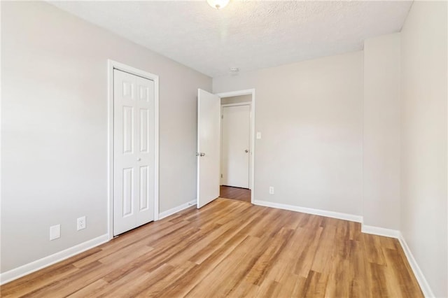 unfurnished bedroom with light hardwood / wood-style floors, a closet, and a textured ceiling