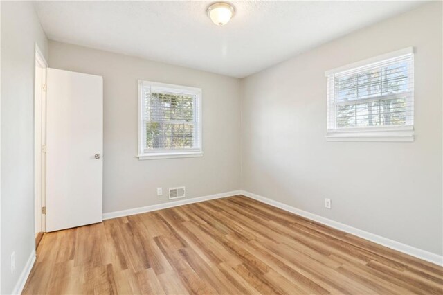 unfurnished room with a healthy amount of sunlight and light hardwood / wood-style floors