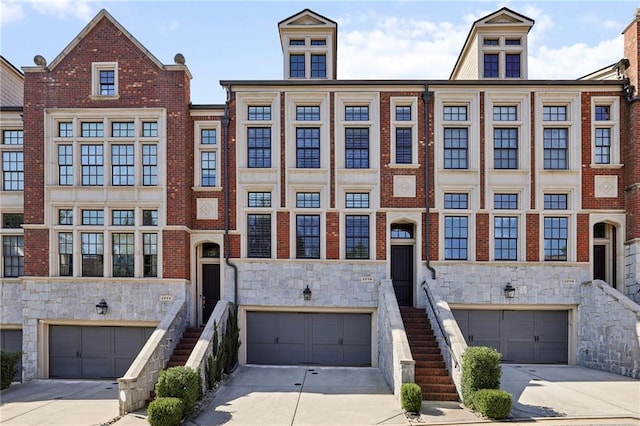 townhome / multi-family property with an attached garage, driveway, and stone siding