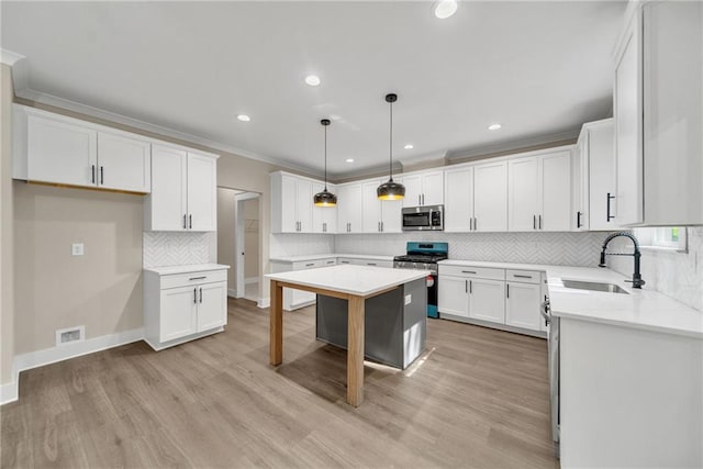 kitchen with light wood finished floors, appliances with stainless steel finishes, crown molding, white cabinetry, and a sink