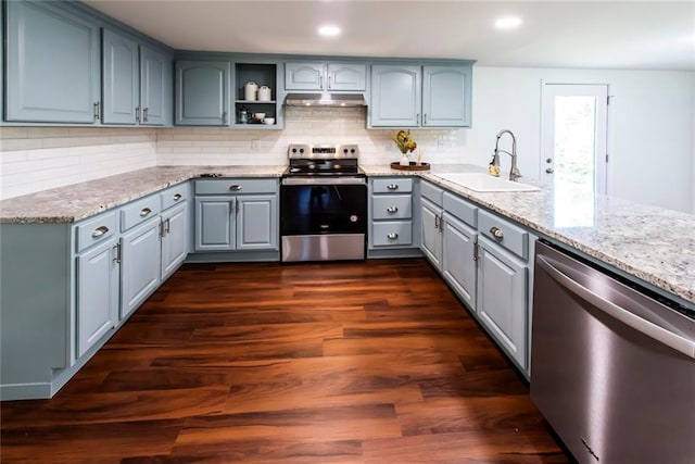 kitchen featuring appliances with stainless steel finishes, sink, decorative backsplash, light stone counters, and dark wood-type flooring