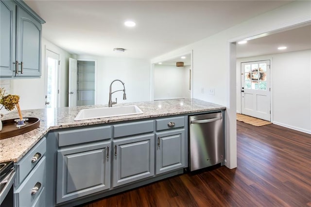 kitchen featuring appliances with stainless steel finishes, kitchen peninsula, light stone counters, dark hardwood / wood-style floors, and sink