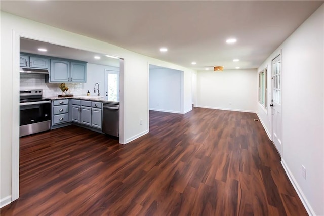 kitchen with dark wood-type flooring, stainless steel appliances, gray cabinets, backsplash, and sink