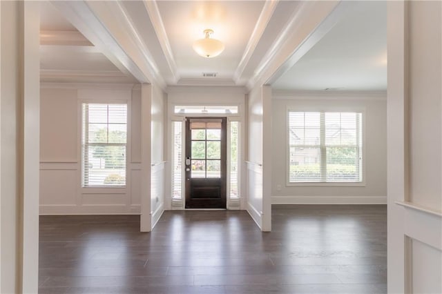 foyer entrance with ornamental molding, a decorative wall, dark wood-type flooring, and wainscoting