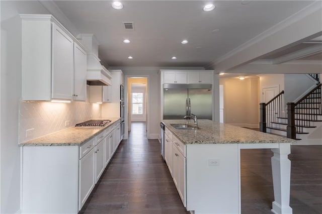 kitchen with stainless steel appliances, ornamental molding, recessed lighting, dark wood finished floors, and a kitchen island with sink
