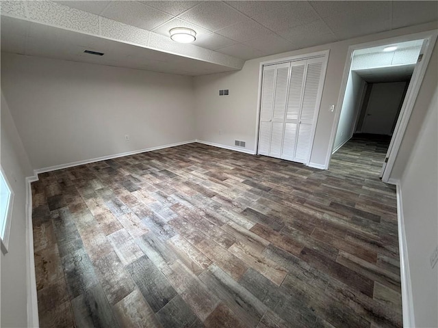 interior space featuring dark hardwood / wood-style floors, a closet, and a drop ceiling