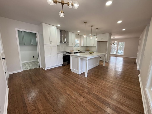 kitchen featuring white cabinetry, a center island, hanging light fixtures, electric range, and wall chimney range hood