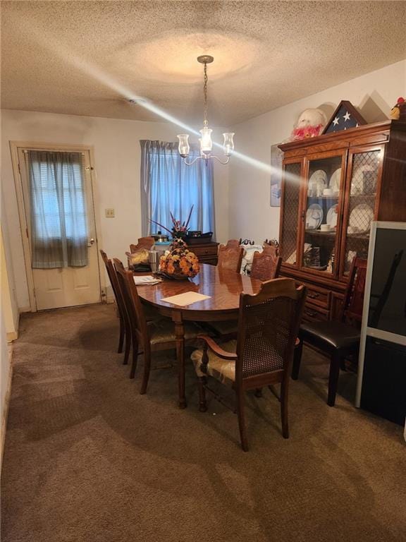 carpeted dining area with a notable chandelier and a textured ceiling