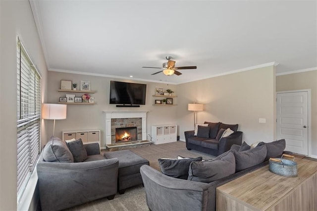 living area with crown molding, ceiling fan, and a stone fireplace