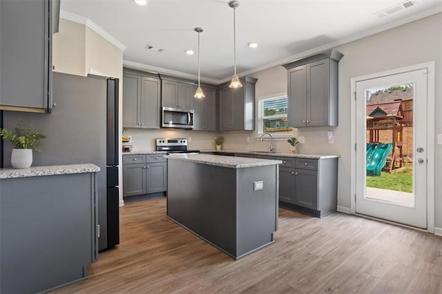 kitchen featuring stainless steel appliances, gray cabinets, crown molding, a sink, and a center island