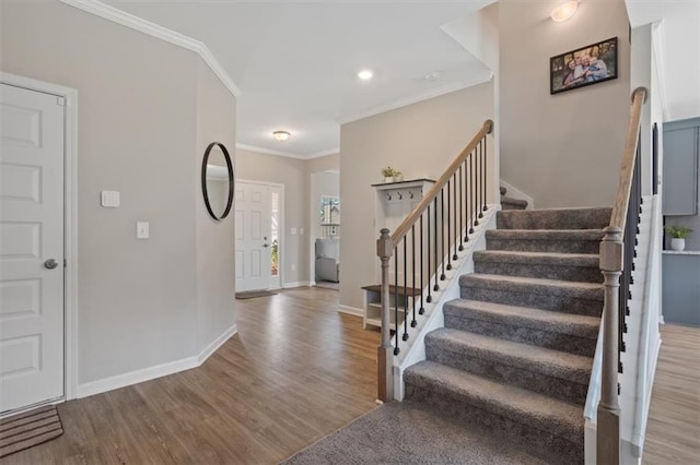 foyer entrance with wood finished floors, stairway, crown molding, and baseboards