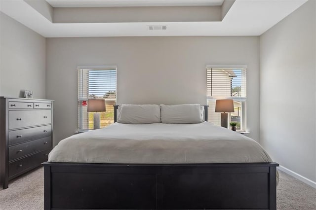 bedroom with light carpet, multiple windows, and baseboards