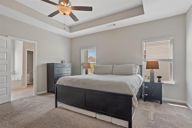 carpeted bedroom with baseboards, a raised ceiling, and ceiling fan