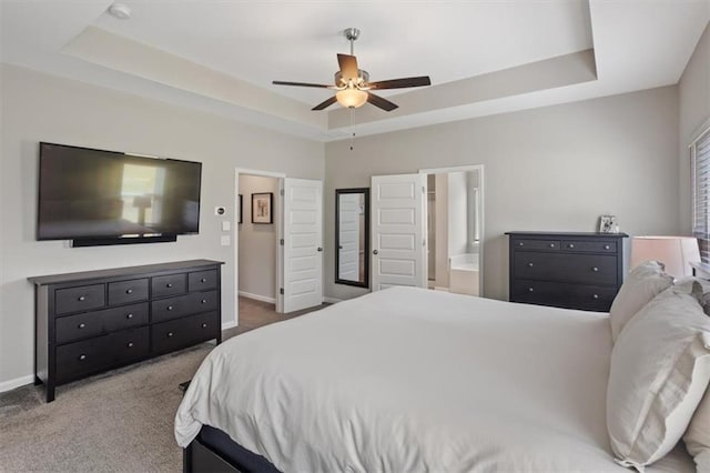 bedroom with a raised ceiling, baseboards, carpet flooring, ceiling fan, and connected bathroom
