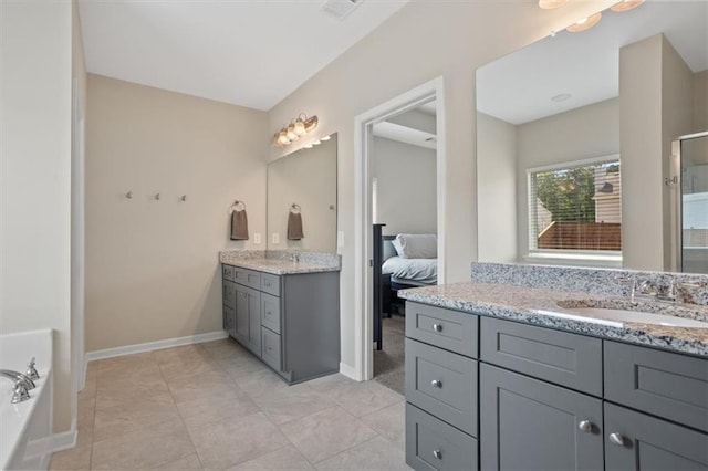 bathroom with two vanities, baseboards, and a tub to relax in