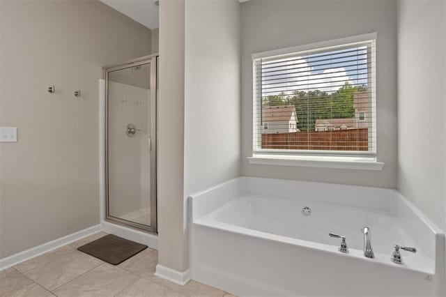 bathroom with a shower stall, a bath, tile patterned flooring, and baseboards