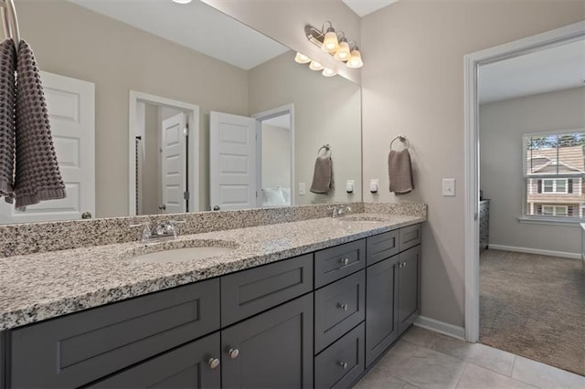 bathroom with double vanity, baseboards, and tile patterned flooring