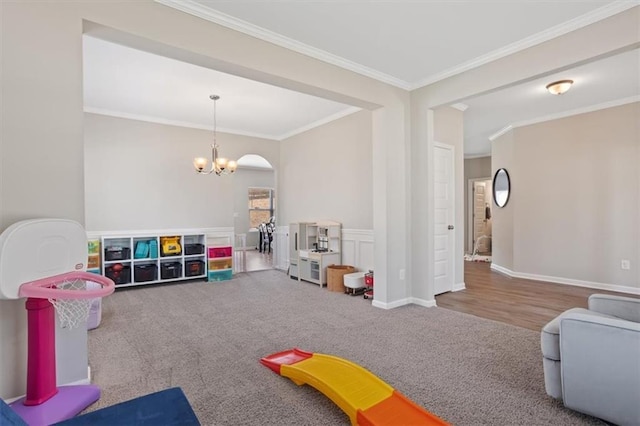 game room with a chandelier, ornamental molding, carpet floors, and arched walkways