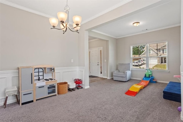 rec room with a chandelier, carpet floors, crown molding, a wainscoted wall, and a decorative wall