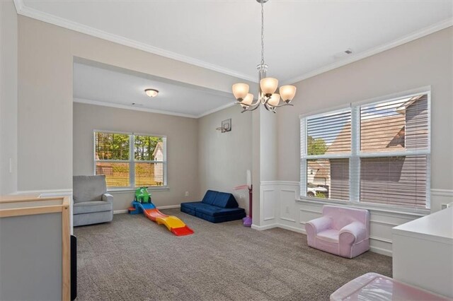 rec room with a chandelier, carpet flooring, ornamental molding, and a wainscoted wall